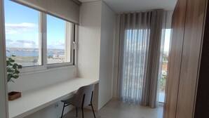 Une chambre moderne dotée d’une grande fenêtre, d’un bureau, d’une chaise et d’un luminaire suspendu.