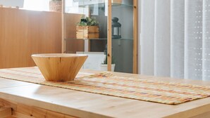 A wooden dining table with a bowl, two pendant lights, and a glass cabinet with plants. - Lisboa - Martim Moniz Central Apartment and Garage (Lisbon)