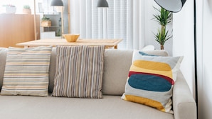 A living room with a sofa, striped pillows, a wooden table, and a floor lamp.