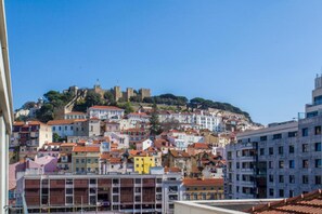 A cityscape with a prominent castle on a hill, colorful buildings, and a mix of modern and traditional architecture.