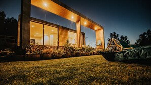 A modern house with large glass windows, a wooden deck, and a well-maintained lawn. - Deluxe Private Pool Bungalow (Celorico de Basto)