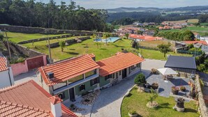 A villa with a red-tiled roof, a swimming pool, and a garden with potted plants. - Quintinha S o Martinho Luxury 2 Suites Villa Eira (Vila do Conde)