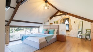 A bedroom with a large bed, wooden beams, a sloped ceiling, and a view of the outdoors. - Quintinha S o Martinho Luxury 2 Suites Villa Eira (Vila do Conde)