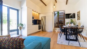 A modern kitchen with a built-in oven and a stainless steel refrigerator. There is a dining area with a wooden table and black chairs. - Quintinha S o Martinho Luxury 2 Suites Villa Eira (Vila do Conde)