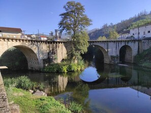 Un puente de piedra sobre un río tranquilo, con vegetación a ambos lados.