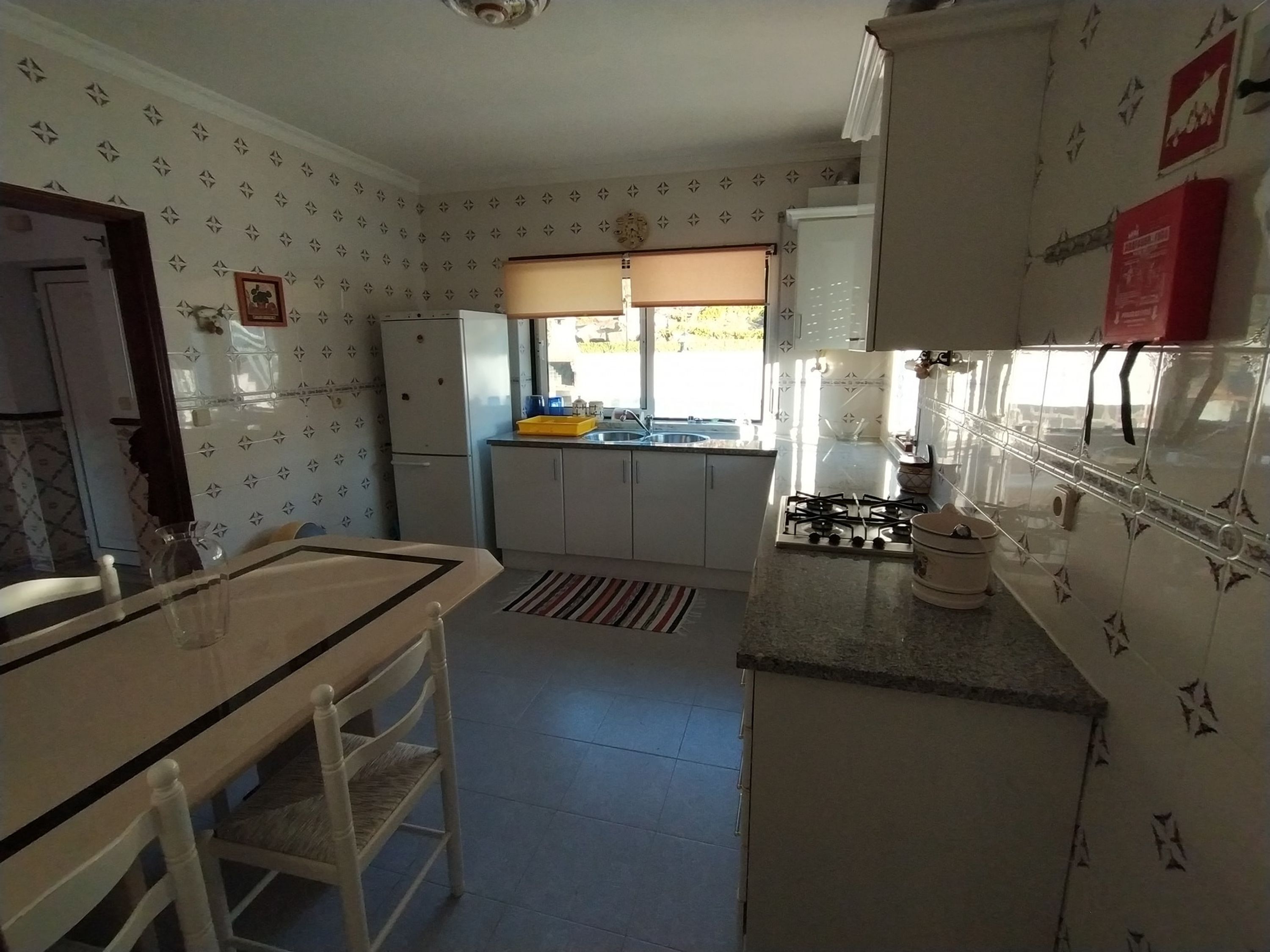 A compact kitchen with white cabinets, a gas stove, a sink, and a window with a view of the outdoors.