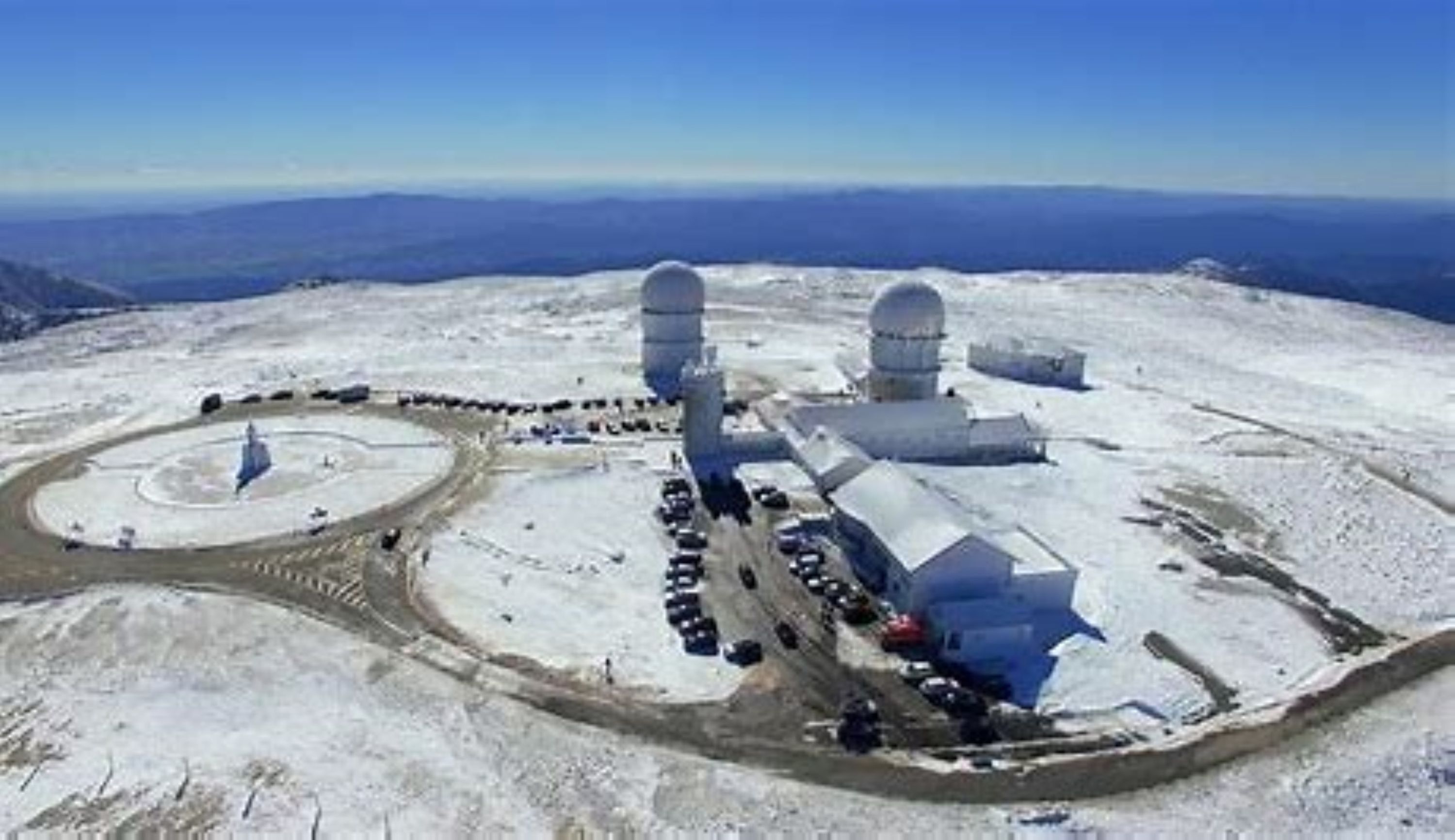 A snow-covered observatory with large domes and a circular driveway.