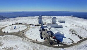 Un observatorio cubierto de nieve con cúpulas grandes y una entrada circular.