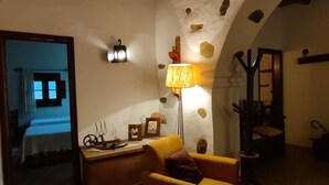 A cozy room with a wooden ceiling, a stone wall, a yellow armchair, a lamp, and a small table with decorative items. - Serra do Caldeir o Private Pool Villa (Almodôvar)