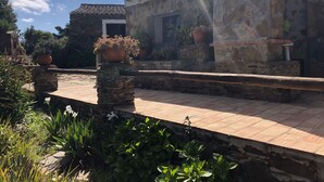 A stone building with a tiled roof, potted plants, and a paved walkway. - Serra do Caldeir o Private Pool Villa (Almodôvar)