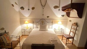 A bedroom with a bed, two bedside tables with lamps, a wooden bench, and a wall-mounted shelf. - Serra do Caldeir o Private Pool Villa (Almodôvar)