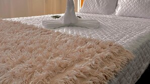 A neatly made bed with a fluffy white rug, a white pillow, and a white decorative item on the bed. - Nice Flat 150 mt Beach With Garage (Portimão)