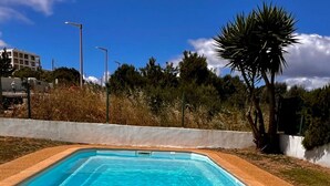 A rectangular swimming pool with clear blue water, surrounded by a tiled deck and a low wall. - Nice Flat 150 mt Beach With Garage (Portimão)