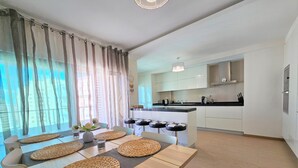 A modern kitchen with white cabinets, a black countertop, and a hanging light fixture. - Superior Garage Balcony Praia da Rocha Prime Flat (Portimão)