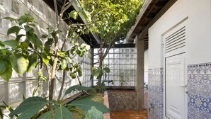 A courtyard with a tiled floor, a door with decorative tiles, and a glass partition with a plant. - Private Pool Villa 20min by Porto (Oliveira De Azemeis)