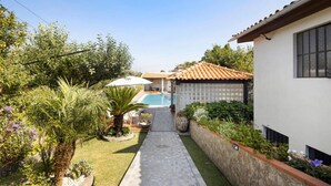 A residential property with a swimming pool, a stone pathway, and a garden with various plants and a palm tree. - Private Pool Villa 20min by Porto (Oliveira De Azemeis)