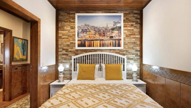 A hotel room with a bed, a nightstand, a framed picture of a cityscape, and a wooden ceiling. - Private Pool Villa 20min by Porto (Oliveira De Azemeis)