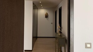 Un corridoio con pavimento in legno, un condizionatore d'aria a parete e un tavolino con un oggetto decorativo.