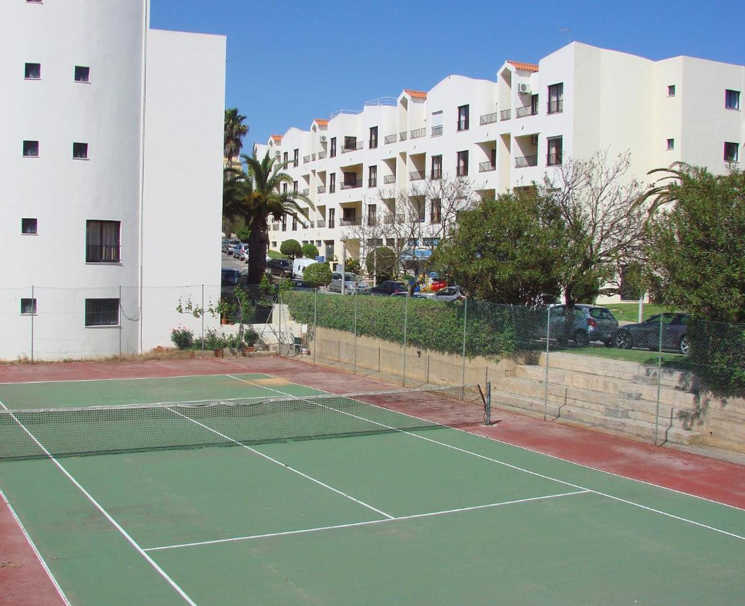 A tennis court surrounded by apartment buildings.