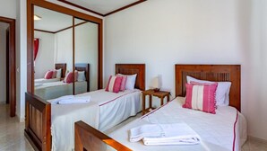 Een hotelkamer met twee bedden, een houten hoofdeinde, een klein nachtkastje en een spiegel.