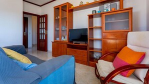 Een woonkamer met twee banken, een televisie en houten kasten.