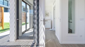 Ein modernes Interieur mit Glastür zu einem Flur, einer weißen Tür mit Glasfenster und einem hellen Boden.