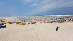 Ein Strand mit Menschen, Sonnenschirmen und einer felsigen Küste.
