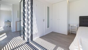 Ein modernes Schlafzimmer mit einem großen Bett, einem Nachttisch und einem Kleiderschrank.
