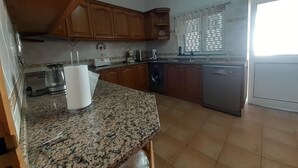 Una cocina con encimeras de granito, armarios de madera, cafetera, tostadora y lavavajillas.