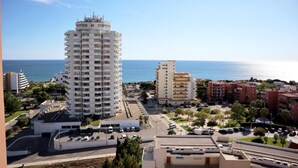 A high-rise building with multiple balconies, a parking area, and a view of the sea. - Green Tower Sea View With Garage and Balcony (Portimão)