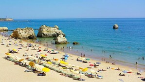 A beach with numerous umbrellas and people enjoying the water. - Green Tower Sea View With Garage and Balcony (Portimão)