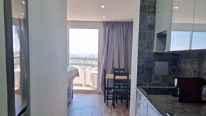A modern kitchen with white cabinets, a granite countertop, and a dining area with a table and chairs. - Green Tower Sea View With Garage and Balcony (Portimão)
