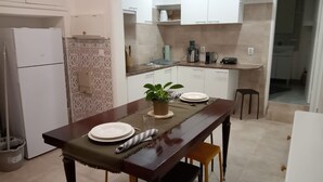 Una cocina compacta con armarios blancos, horno integrado y un comedor con mesa de madera dispuesta para dos personas.