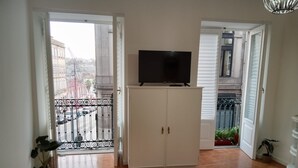 Una sala de estar con televisor sobre un mueble bajo, una mesita y una alfombra amarilla.
