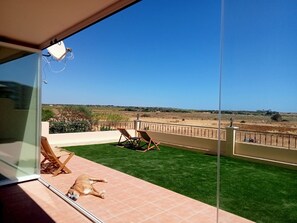A balcony with a clear view of a grassy area and distant landscape. - Beach Front View Armacao de Pera Flat With Terrace (Silves)