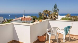 Une terrasse sur le toit offrant une vue sur la mer, avec des chaises blanches et un panier.