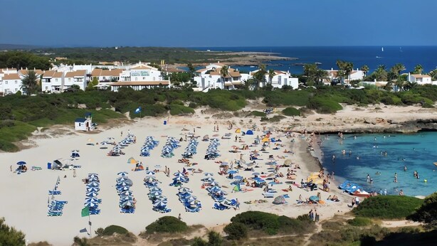Une station balnéaire dotée de parasols, d’une plage de sable et offrant une vue sur la mer.