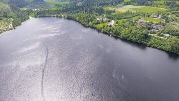 Ein Anwesen am See mit Seeblick, umgeben von bewaldeten Hügeln und einem kleinen Dorf.