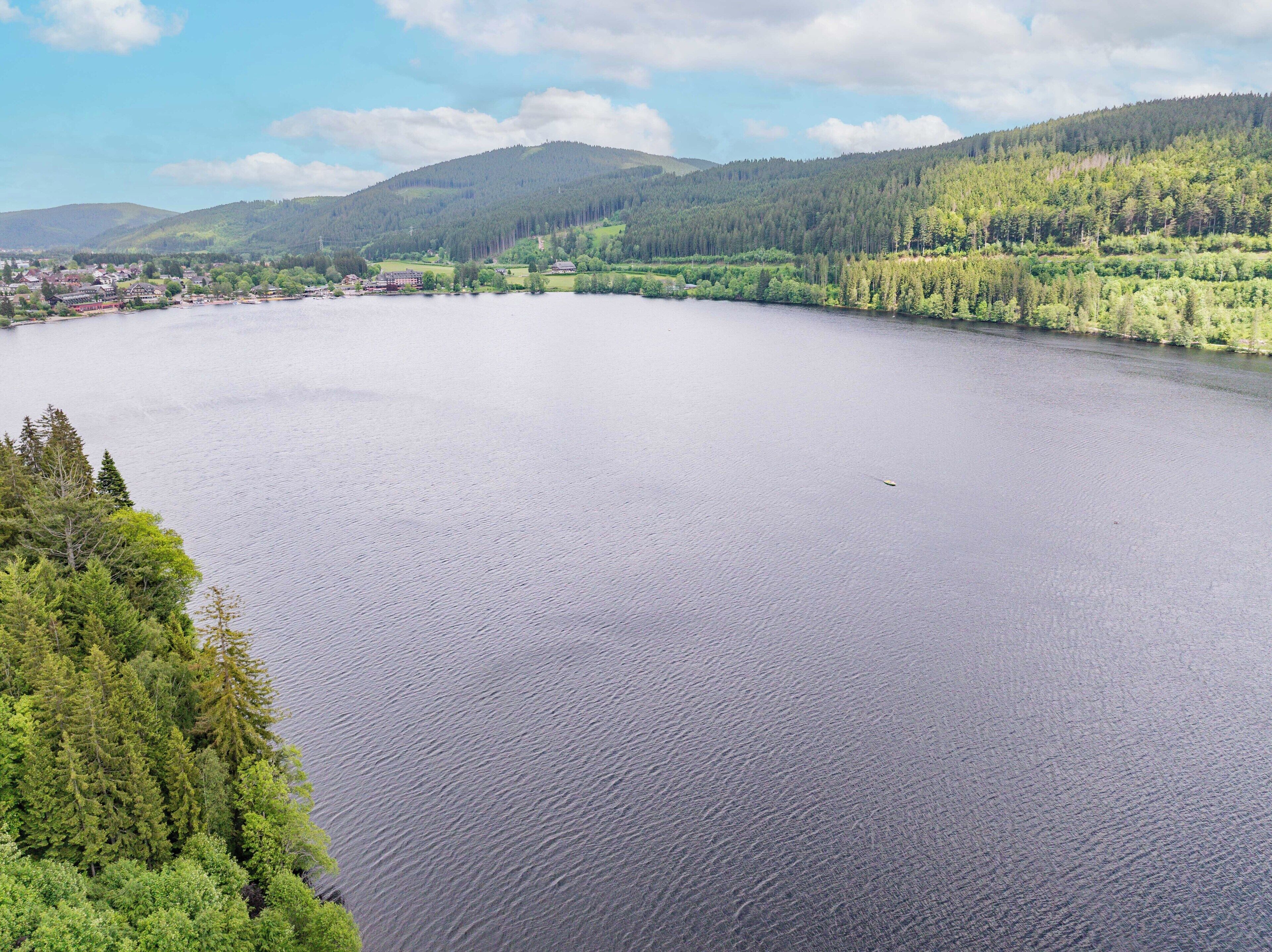 Un grand lac entouré de collines boisées et d’une petite ville.