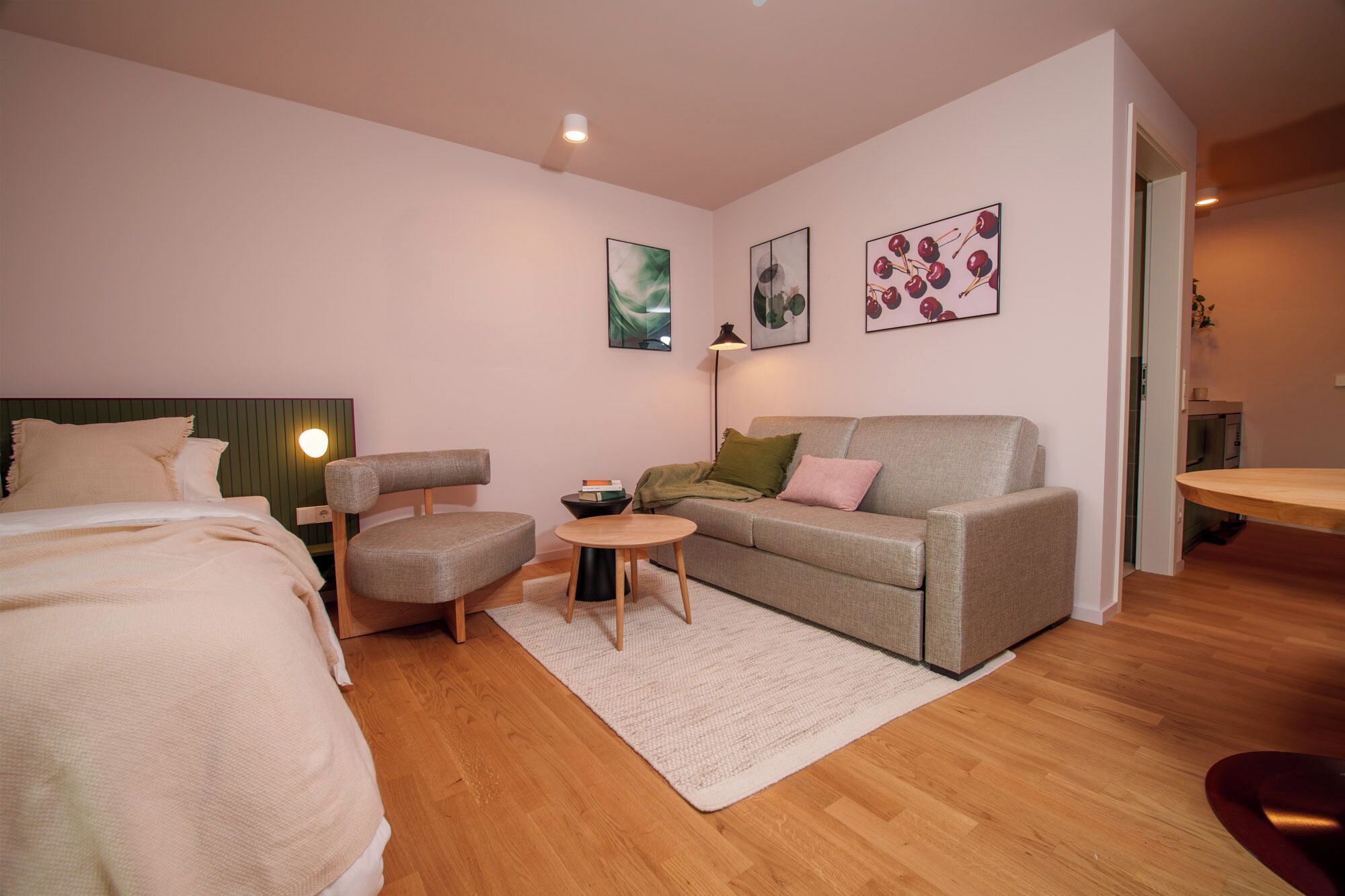 Un dormitorio moderno con cama, sofá, sillón, una mesita y obras de arte en las paredes.