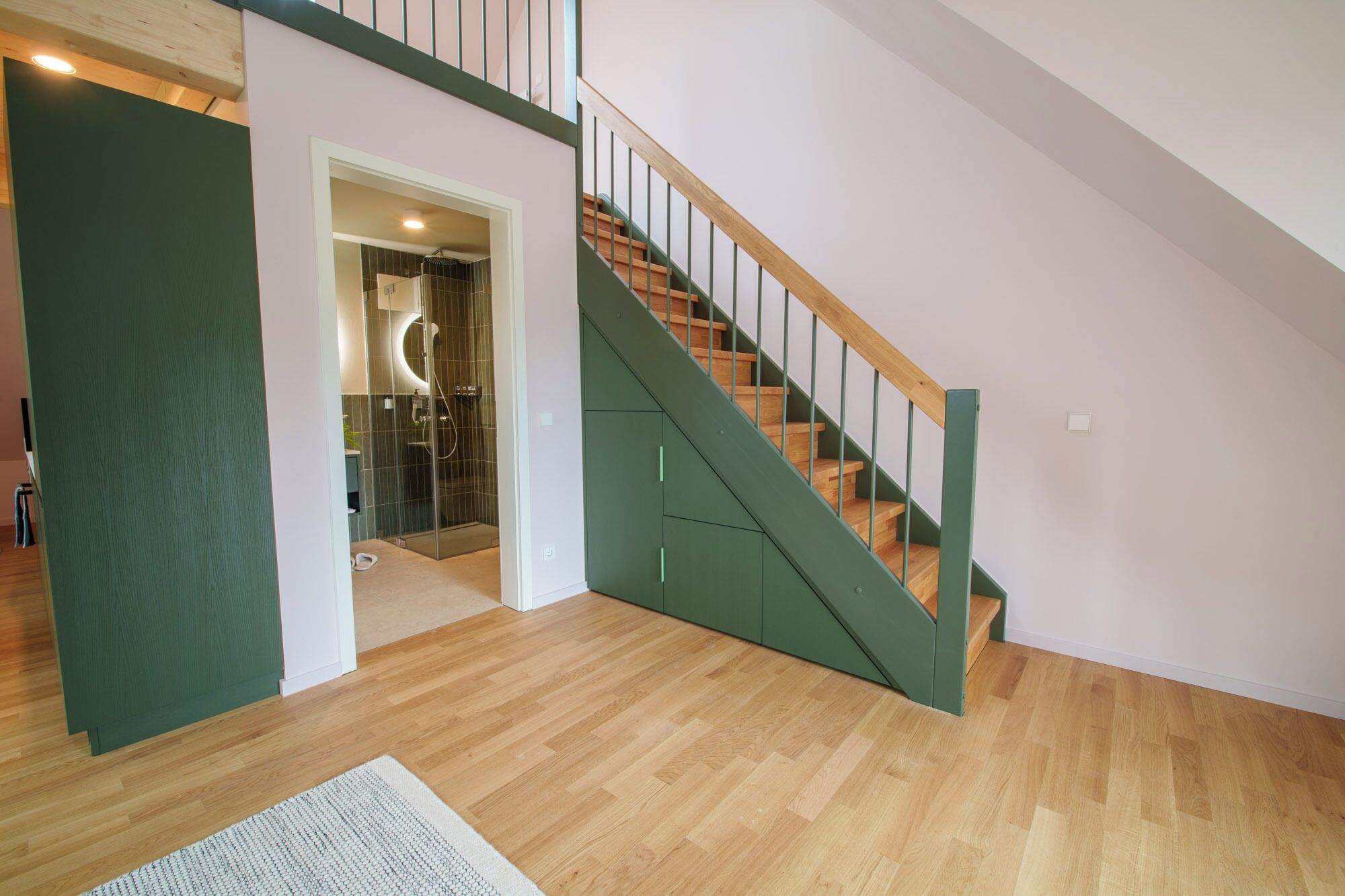 A modern interior with a wooden staircase and a glass-enclosed shower area.