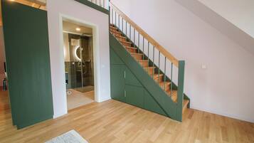 A modern interior with a wooden staircase and a glass-enclosed shower area.