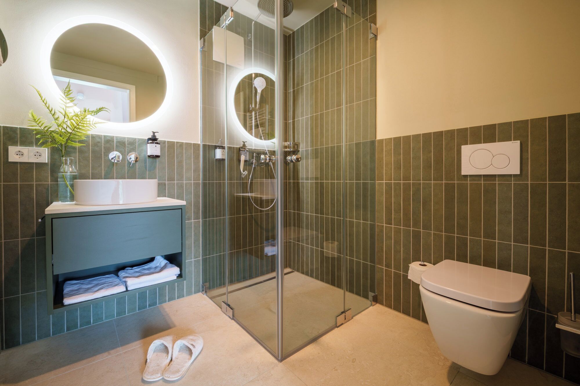 Une salle de bain moderne avec une douche à parois de verre, des toilettes blanches et un lavabo avec un miroir au-dessus.