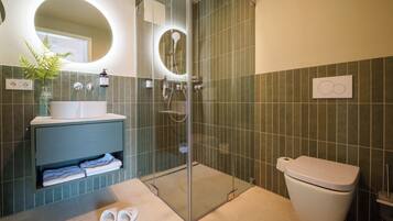 Une salle de bain moderne avec une douche à parois de verre, des toilettes blanches et un lavabo avec un miroir au-dessus.