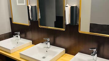 A public restroom with three sinks, each with a mirror and a paper towel dispenser.