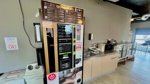 A coffee machine with a menu and a GEORGIA.CAFE sign, a coffee maker, and a counter with a window view. - Mikami Asakusabashi Hotel (Tokyo)
