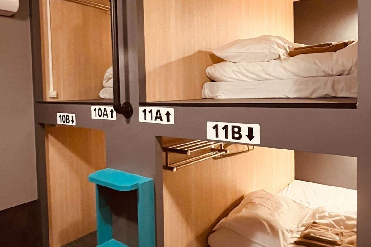 Une chambre de type dortoir avec des lits superposés numérotés 10A, 10B, 11A et 11B. On y trouve un escabeau bleu et un luminaire suspendu.