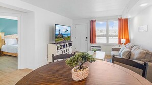Ein modernes Wohnzimmer mit Fernseher, Esstisch und Sofa.