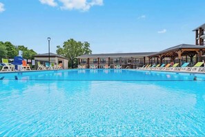 A swimming pool with lounge chairs and a building in the background. - 111 Indoor pool walk to Landing & Convention Center (Branson)