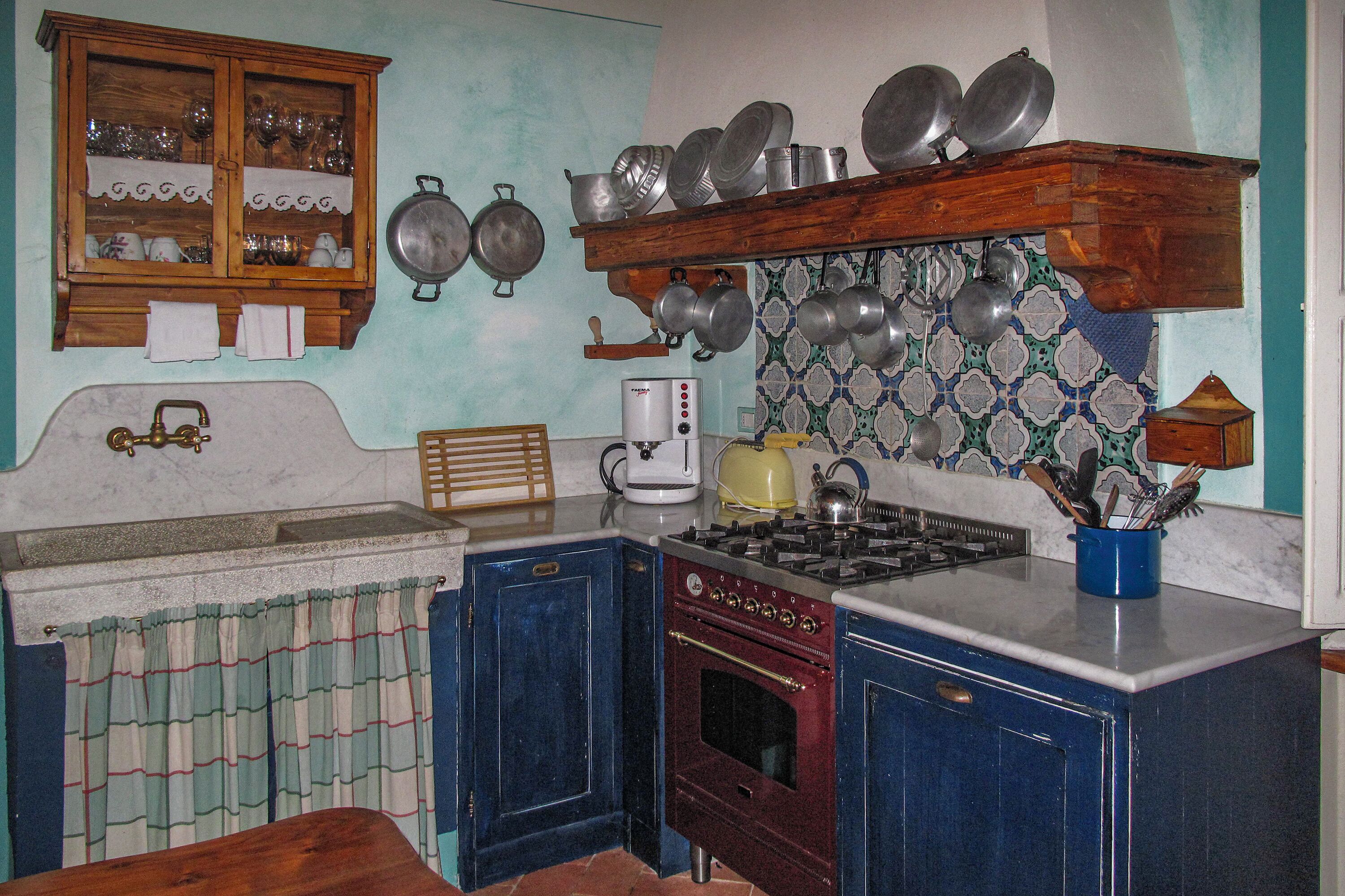 A vintage kitchen with a gas stove, wooden cabinets, and a tiled backsplash.